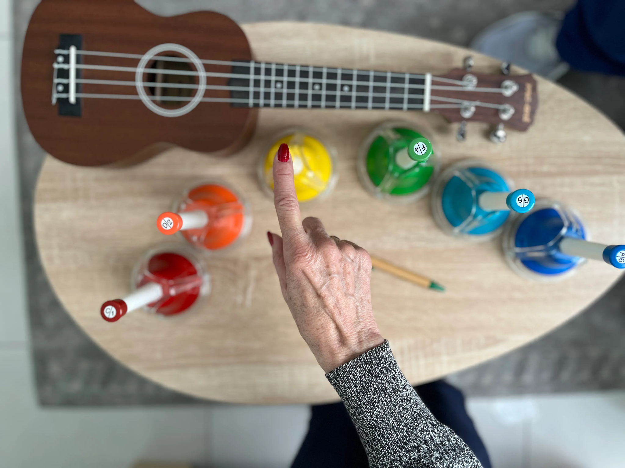 Mano de una persona mayor durante una actividad musical con campanas de colores